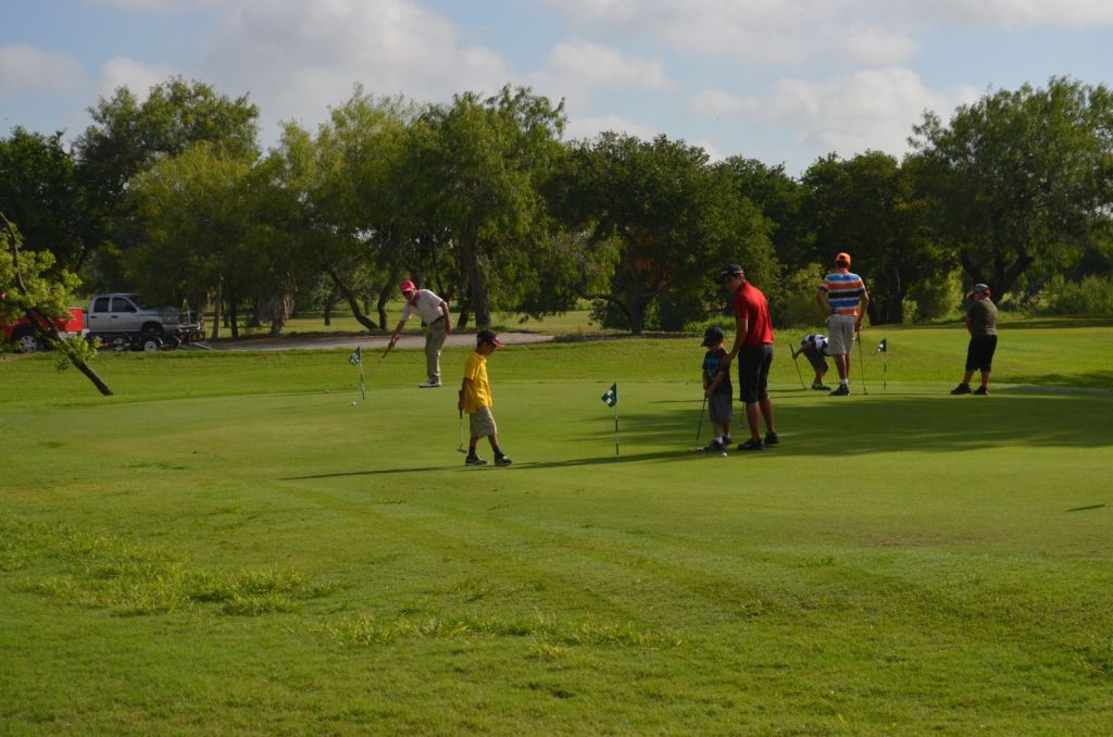 Junior golf players with instructors on golf course green