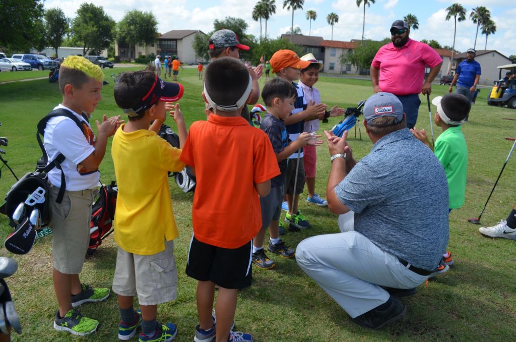 Junior golfers in a huddle with instructor